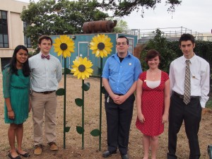 People standing beside sunflower